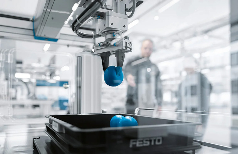 机器人使用 Festo 的 GripperAI 在工作单元中拾取泡沫球。